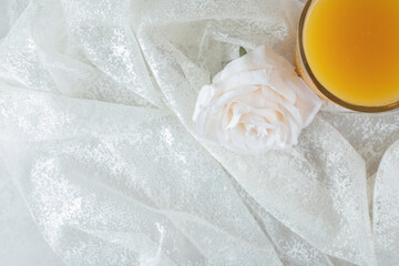 Glass of orange juice with flowers on white cloth