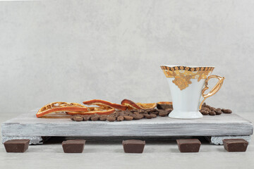 Cup of espresso with chocolate and orange slices on wooden board
