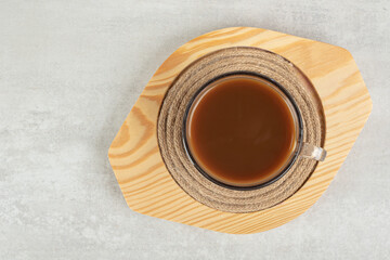 Glass of hot coffee on wooden plate