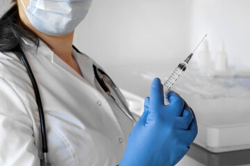 Nurse pushing air out of syringe for vaccine injection. Doctor wearing blue gloves and medical...