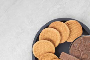 Glass of coffee and various biscuits on dark board
