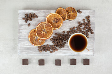 Fototapeta na wymiar Cup of espresso with chocolate and orange slices on wooden board