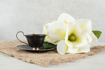 Fototapeta na wymiar Cup of espresso and white flowers on burlap