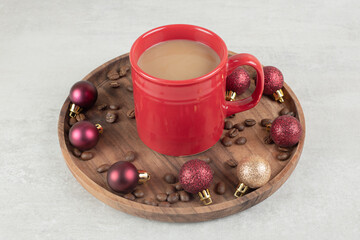 Obraz na płótnie Canvas Cup of coffee with Christmas ornaments on wooden plate