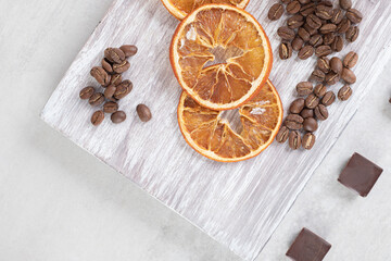 Orange slices, coffee beans and chocolate on wooden board