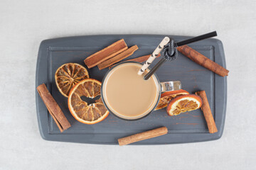 Tasty coffee, cinnamon sticks and orange slices on dark plate