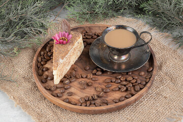 Slice of cake, coffee and coffee beans on wooden plate