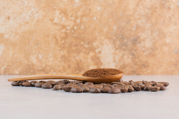 A wooden spoon of cacao powder with coffee beans