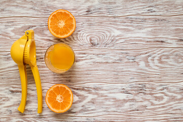 Hand juicer, a glass of freshly squeezed juice and a tangerine on a wooden table, top view