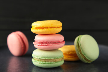Colorful macarons cakes on dark background. Small French cakes. Sweet and colorful french macaroons.