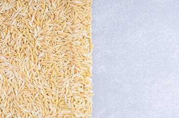 Heap of brown rice tidily arranged on marble background
