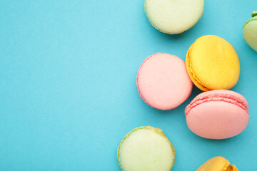 French colorful macarons on blue background. Space for text