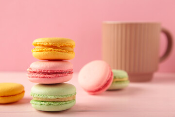 French macarons with cup on pink background.