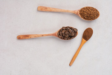 Three wooden spoons full of coffee beans and cacao powder