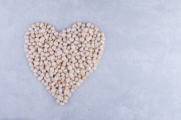 Pile of chickpeas arranged into a heart shape on marble background