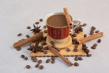 A cup of hot coffee with star anise and cinnamon sticks on crackers