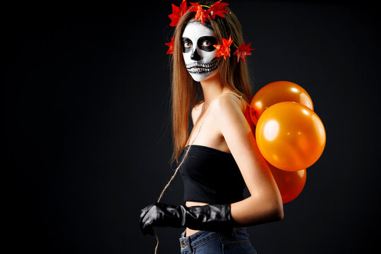 Beautiful woman with Halloween sugar skull makeup with balloons. Shh.. Close up studio portrait.