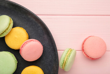 Colorful macarons cakes on pink background. Small French cakes on plate. Space for text