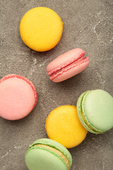 Colorful macarons cakes on grey background. Small French cakes. Vertical photo
