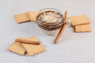 A cup of delicious drink with crackers and cinnamon sticks