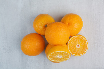 Ripe whole and half cut oranges on stone background