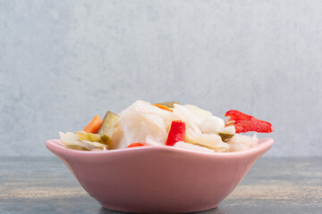 A pink plate full of salty vegetables on marble background