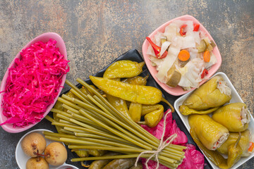 A dark plate full of pickled cucumbers and red salty cabbage on marble background