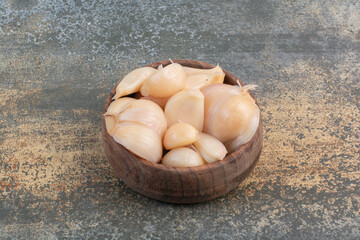 A wooden bowl of salty garlics on marble background