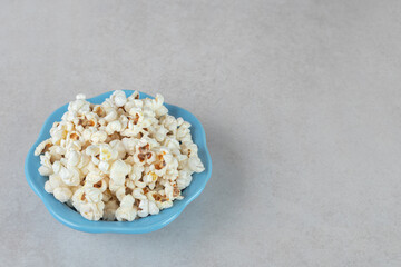 Crunchy popcorn on a small blue platter on marble background