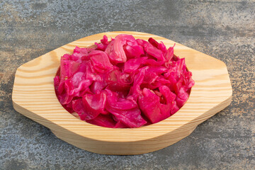 A wooden plate full of red salty cabbage on marble background