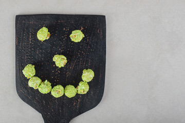 Popcorn candy arranged into a smiley face on a wooden board on marble background