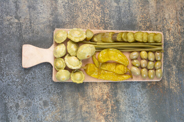 A wooden board of salty vegetables on marble background