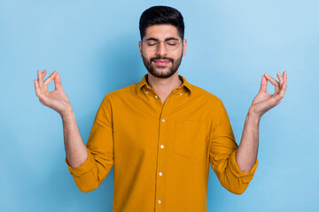 Naklejka premium Photo of peaceful carefree handsome man dressed yellow shirt closed eyes hands fingers meditate isolated on blue color background