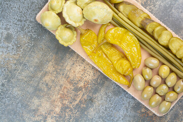 A wooden board of salty vegetables on marble background