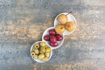 A three plate of olives and delicious fruits on marble background