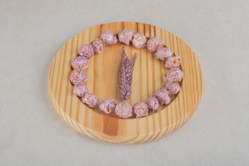 Single stalk of wheat ringed with flavored popcorn on a wooden platter on marble background