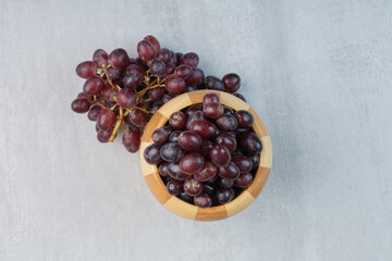Bunch of purple grapes in bucket and on table