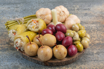 A wooden board full of salty vegetables with sweet fruits on marble background