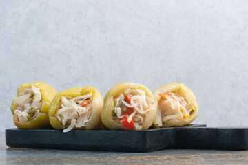 A dark board with salty peppers and cabbage on white background