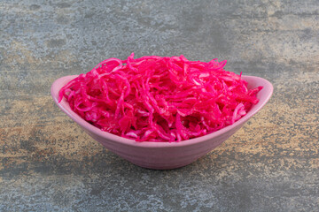 A pink plate full of red salty cabbage on marble background