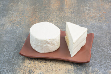 White whole cheese and slice on brown plate