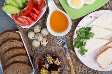 Breakfast table with vegetables, tea, bread and eggs