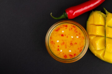 Mango chili jam, cutted mango and and red chili pepper on dark grey background with free space for text - Powered by Adobe