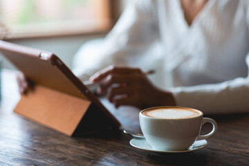 latte coffee cup Asian woman working on a tablet in a cafe