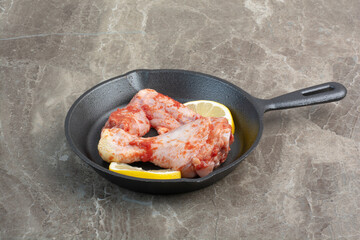 Raw chicken meat with spices and lemon on dark pan