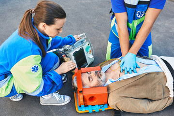 First aid. Cardiopulmonary resuscitation and chest compressions to injured unconscious male from ambulance workers