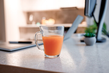 Glass of tasty orange juice standing on kitchen table