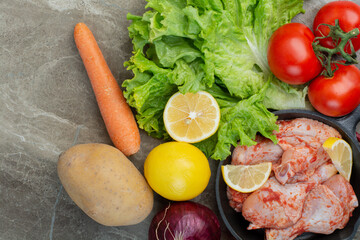 Fresh vegetables with raw chicken on marble background