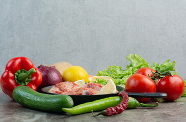 Fresh vegetables with raw chicken on marble background