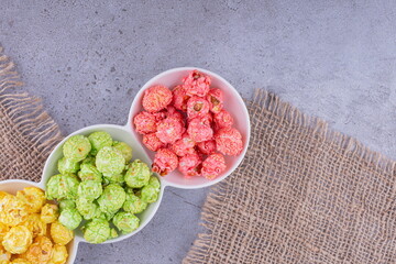 Assorted servings of popcorn candy in a triple-platter on marble background